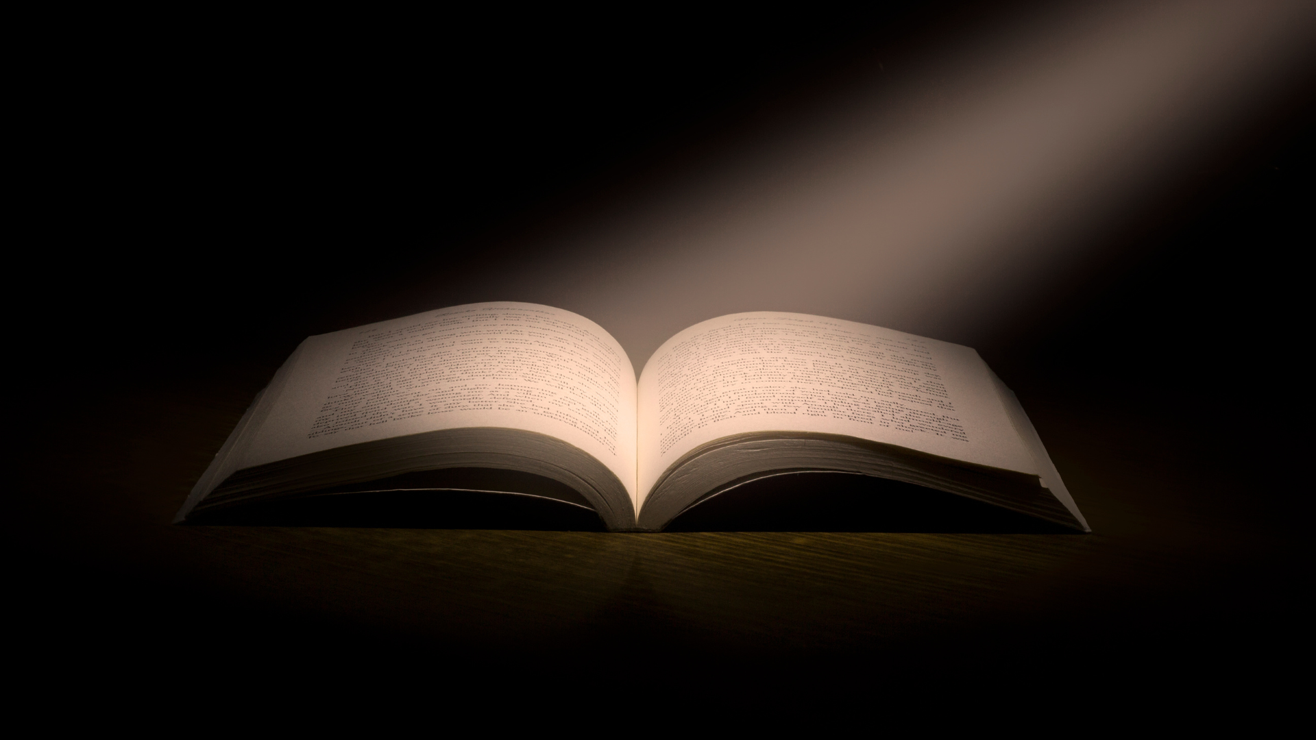 Open book under spotlight in darkness.